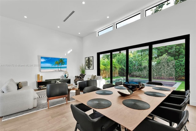 dining space featuring a towering ceiling and light hardwood / wood-style floors