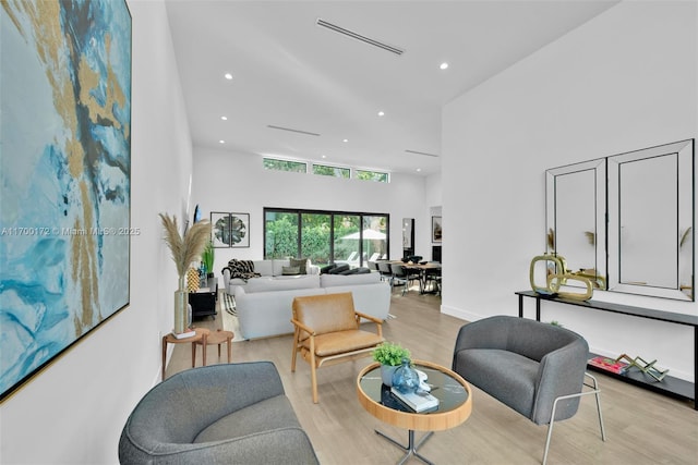 living room with a towering ceiling and light hardwood / wood-style flooring