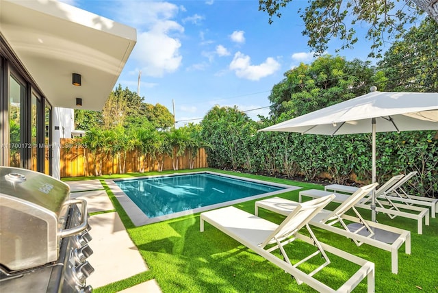 view of swimming pool featuring area for grilling and a lawn