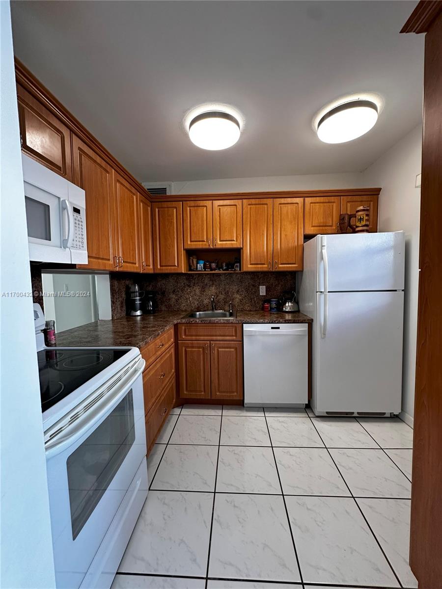 kitchen featuring white appliances, sink, and tasteful backsplash