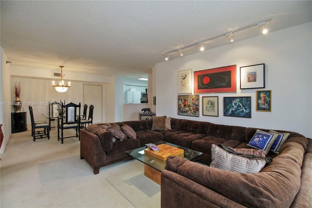 carpeted living room featuring rail lighting, a notable chandelier, and a textured ceiling