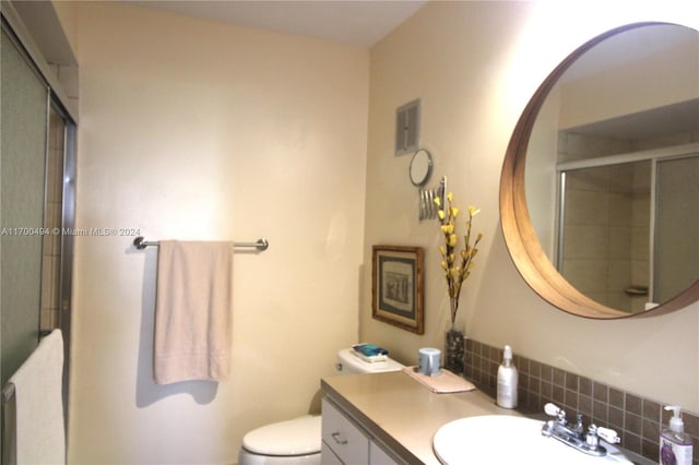 bathroom featuring decorative backsplash, vanity, toilet, and a shower with shower door