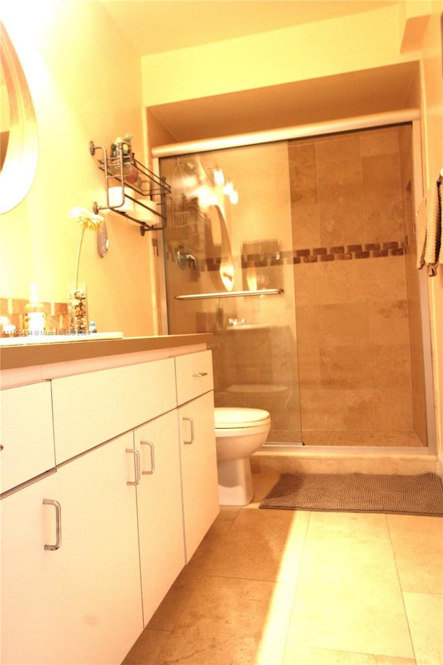 bathroom with tile patterned flooring, vanity, toilet, and a shower with door