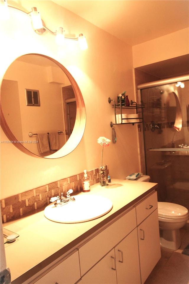 bathroom with an enclosed shower, vanity, and toilet