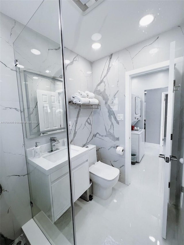 bathroom with separate washer and dryer, a shower with door, vanity, and tile walls