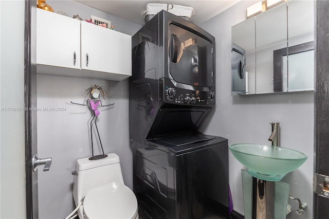 bathroom featuring stacked washer and dryer, toilet, and sink