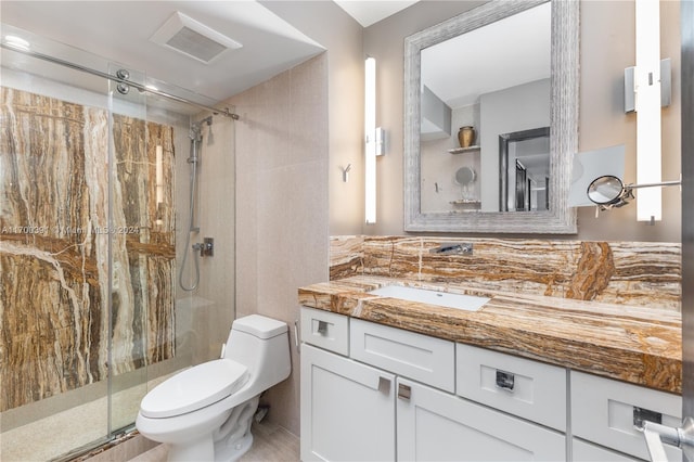 bathroom featuring vanity, toilet, a shower with door, and backsplash