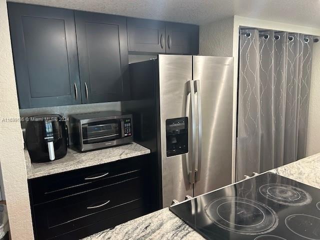 kitchen featuring light stone countertops, stainless steel fridge with ice dispenser, a textured ceiling, and black electric cooktop