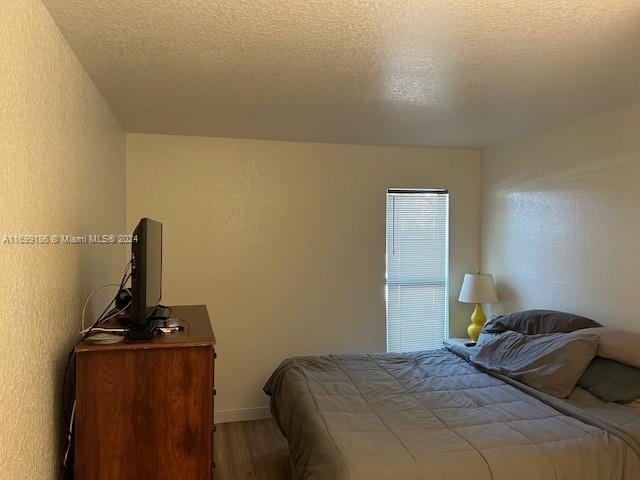 bedroom with hardwood / wood-style floors and a textured ceiling