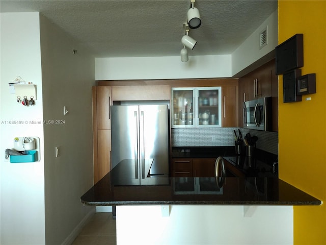 kitchen with kitchen peninsula, appliances with stainless steel finishes, a breakfast bar, and backsplash