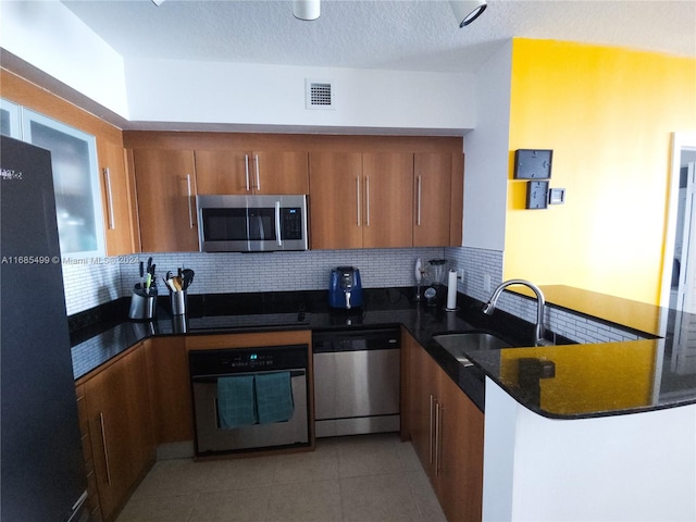 kitchen featuring kitchen peninsula, sink, backsplash, and black appliances