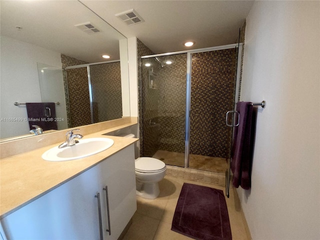 bathroom featuring tile patterned flooring, vanity, toilet, and a shower with shower door