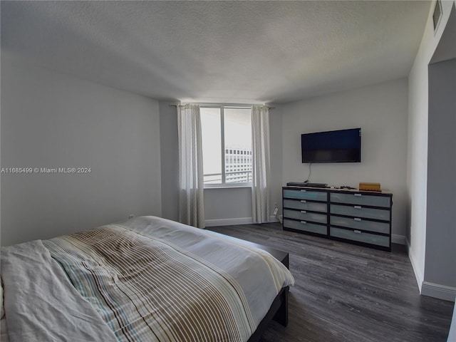 bedroom featuring a textured ceiling and dark hardwood / wood-style floors