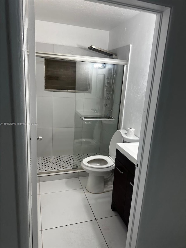 full bath with vanity, tile patterned floors, toilet, and a shower stall