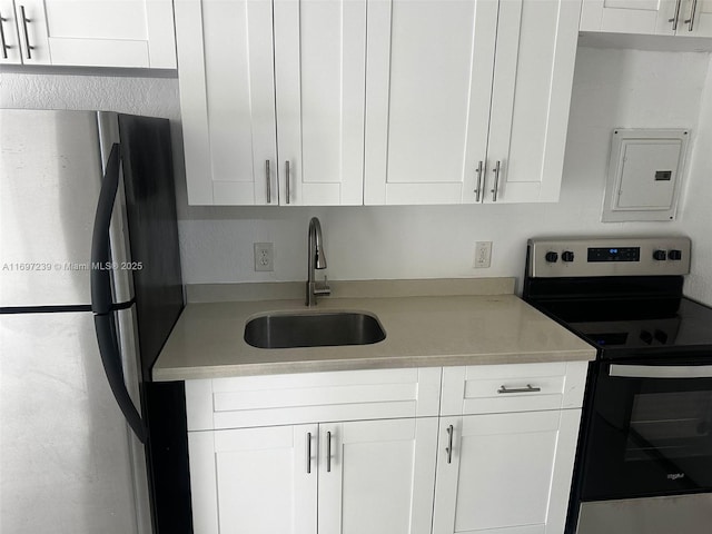 kitchen featuring a sink, appliances with stainless steel finishes, white cabinetry, and light countertops