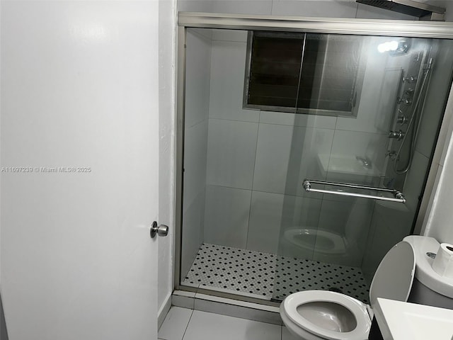 bathroom featuring toilet, tile patterned flooring, and a stall shower