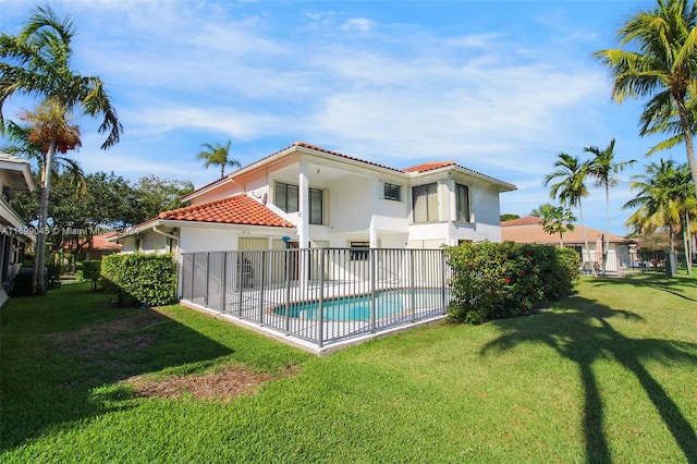 back of property featuring a fenced in pool and a yard