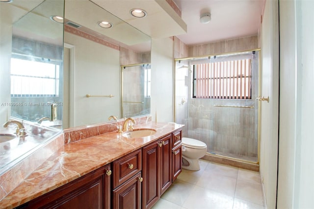 bathroom with tile patterned floors, vanity, a shower with shower door, and toilet