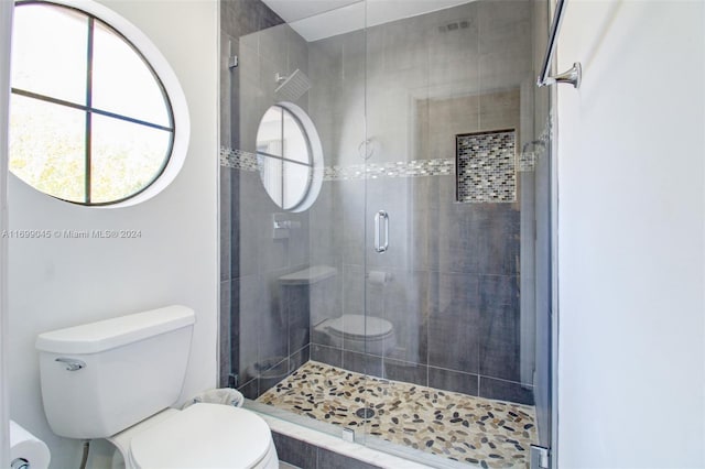 bathroom featuring a shower with shower door and toilet