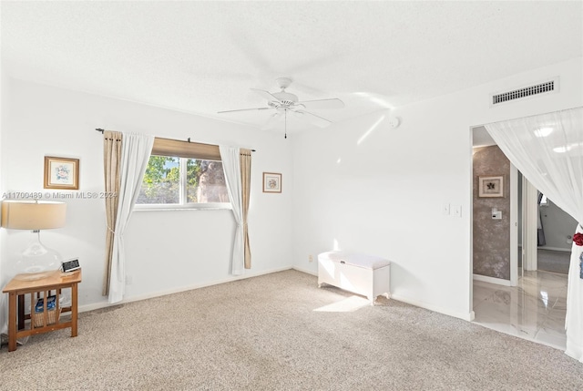 empty room featuring a textured ceiling, carpet floors, and ceiling fan