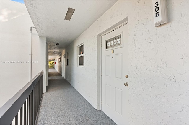 hall with carpet flooring and a textured ceiling