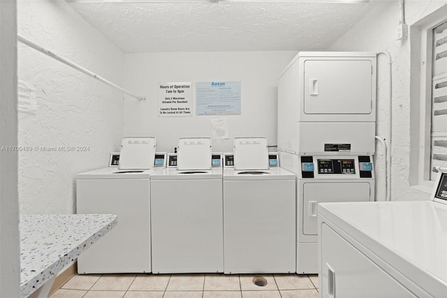 clothes washing area with light tile patterned floors, a textured ceiling, and stacked washer and dryer