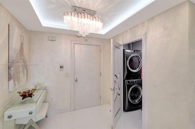 laundry area with a chandelier, light tile patterned floors, and stacked washer / drying machine