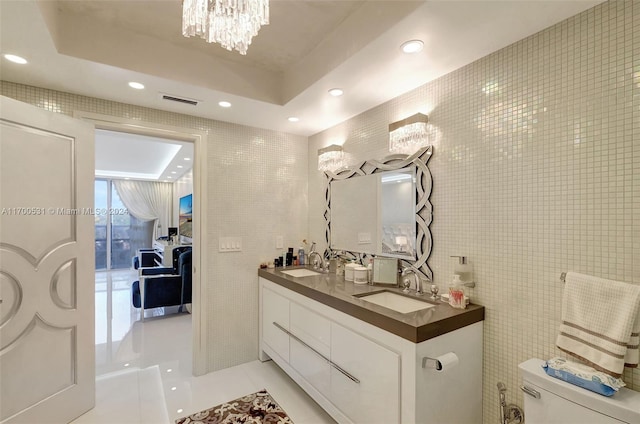 bathroom featuring toilet, tile patterned floors, a raised ceiling, and tile walls