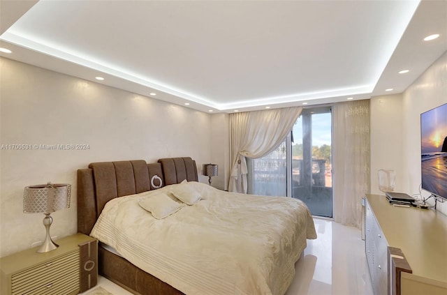 bedroom with access to outside and a raised ceiling