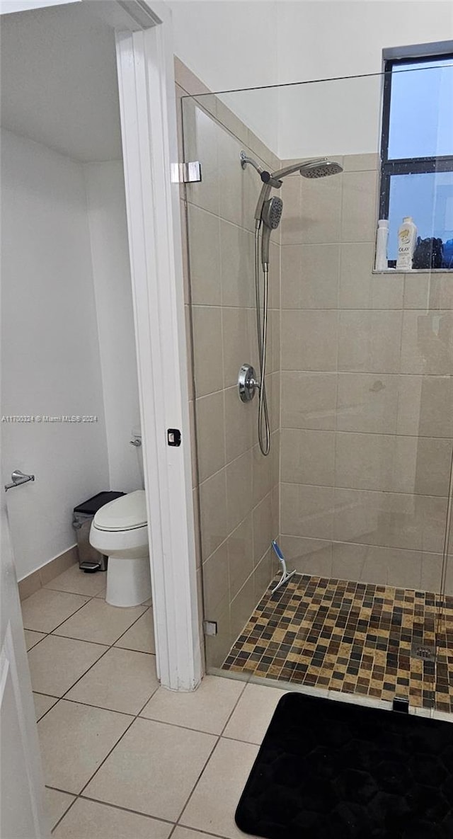 bathroom with tile patterned floors, toilet, and a tile shower