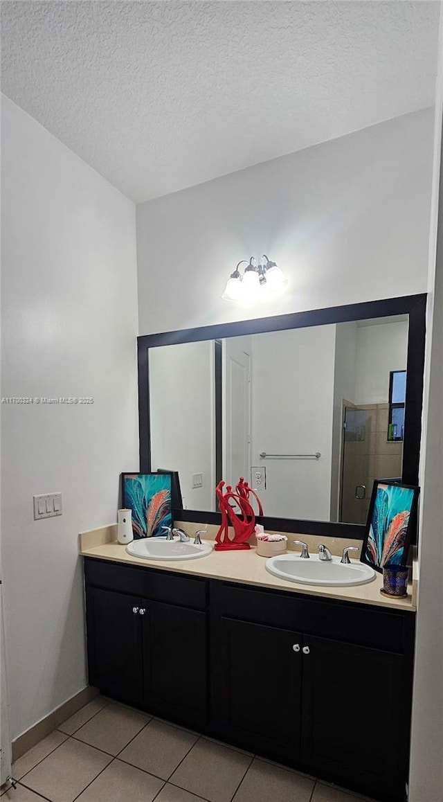 bathroom with a shower with door, vanity, tile patterned floors, and a textured ceiling