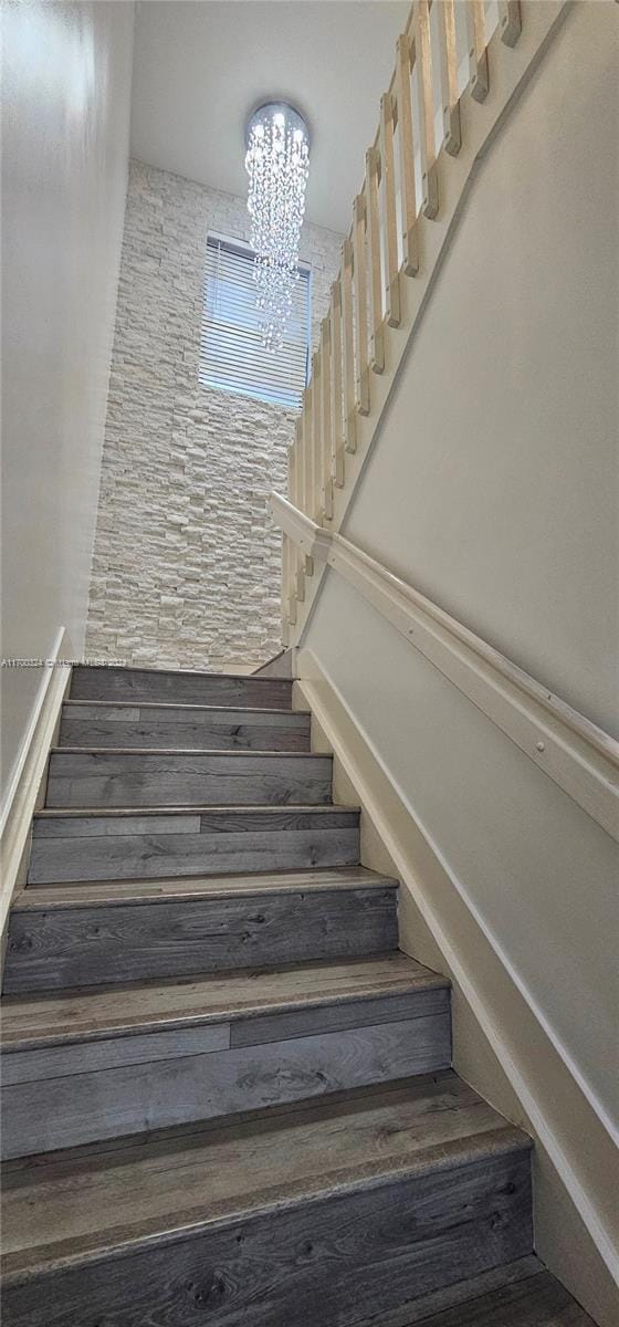 stairway featuring wood-type flooring and a notable chandelier