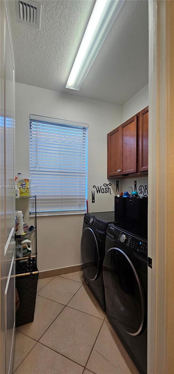 laundry room with cabinets, independent washer and dryer, a textured ceiling, and light tile patterned floors