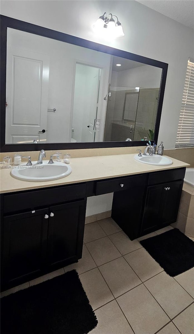 bathroom with tile patterned floors, vanity, and shower with separate bathtub