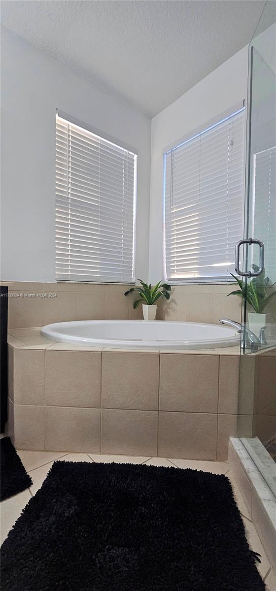 bathroom featuring tile patterned flooring, a textured ceiling, and tiled tub