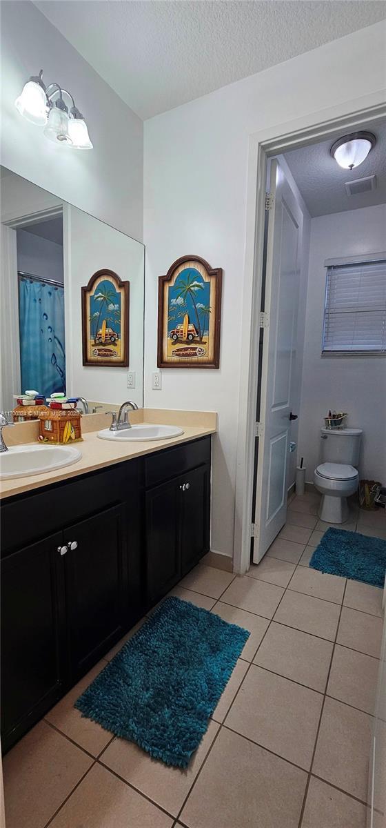 bathroom featuring vanity, tile patterned floors, a textured ceiling, and toilet