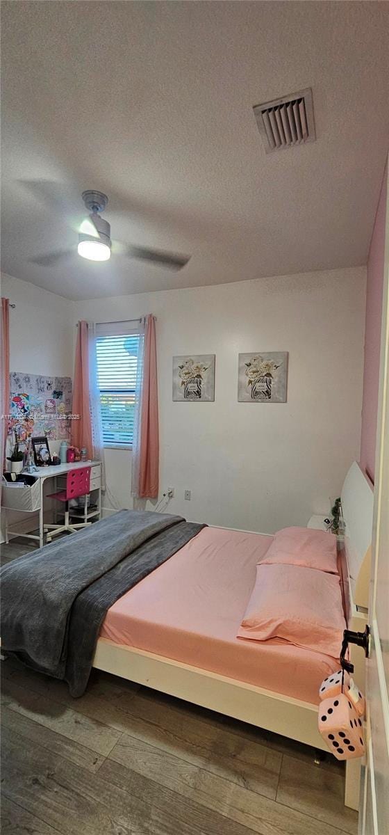 bedroom featuring hardwood / wood-style floors, a textured ceiling, and ceiling fan