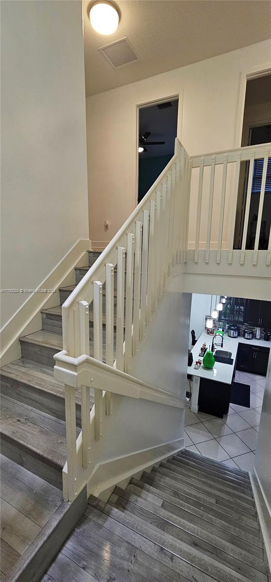 staircase with hardwood / wood-style flooring and ceiling fan