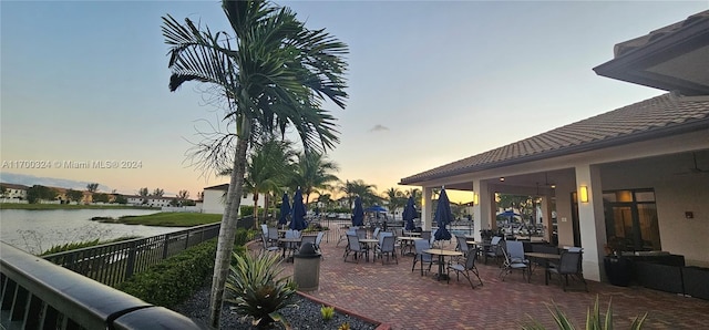 patio terrace at dusk featuring a water view