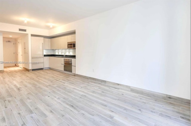 unfurnished living room with sink and light wood-type flooring