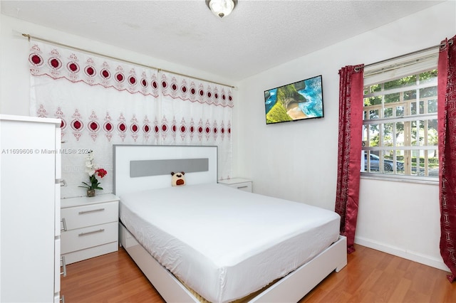 bedroom with light hardwood / wood-style floors and a textured ceiling