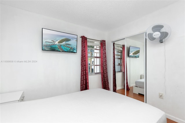 bedroom with a closet, wood-type flooring, and a textured ceiling