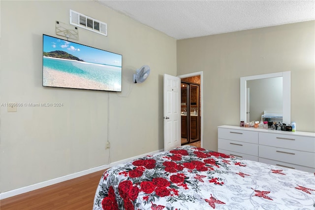 bedroom with hardwood / wood-style floors and a textured ceiling