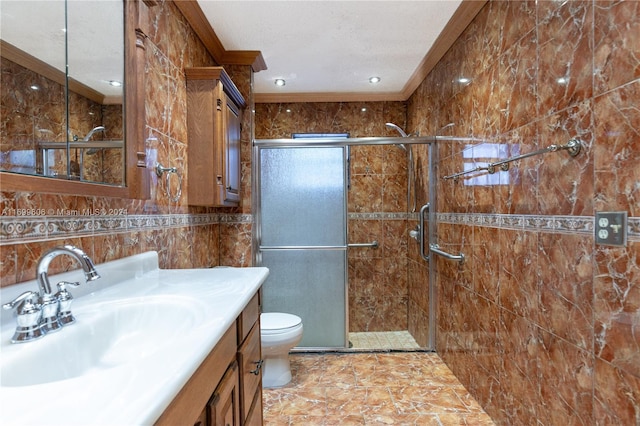 bathroom with vanity, a shower with door, crown molding, tile walls, and toilet