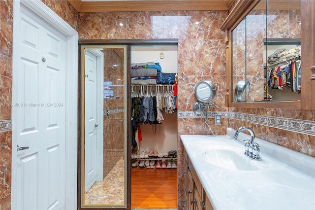 bathroom with vanity, hardwood / wood-style flooring, tile walls, and crown molding