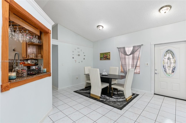 dining area with light tile patterned floors, a textured ceiling, and lofted ceiling