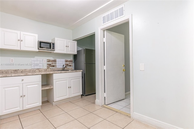 kitchen with white cabinetry, sink, stainless steel appliances, backsplash, and light tile patterned floors