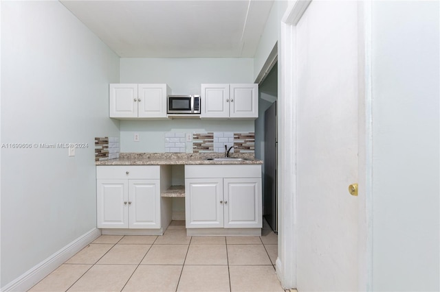 kitchen with white cabinets, sink, decorative backsplash, light tile patterned flooring, and light stone counters