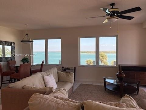 living area featuring plenty of natural light, a ceiling fan, and a water view