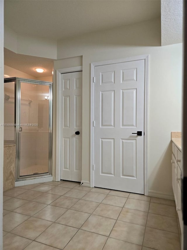 bathroom featuring baseboards, vanity, a shower stall, and tile patterned flooring